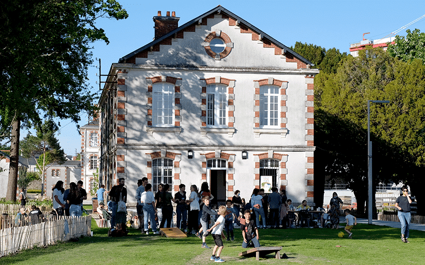 photo d'un groupe de personne dans un jardin devant la facade d'un batiment